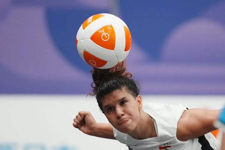 An athlete returning a ball over a curved teqball table during a match.