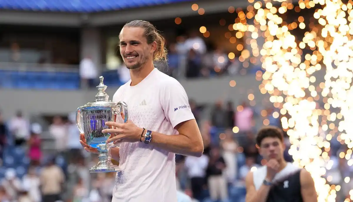 Alexander Zverev lifting the US Open championship trophy in Arthur Ashe Stadium.
